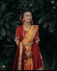 A Maharashtrian bride dressed in a vibrant silk Nauvari saree with golden zari borders, adorned with traditional jewellery, ready for a wedding ceremony.